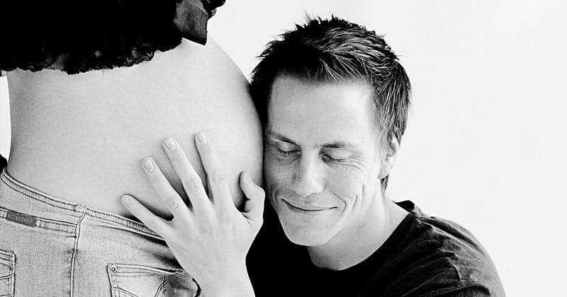 Werdender Vater hört am Bauch der schwangeren Partnerin